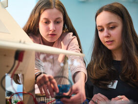 Zwei Mädchen arbeiten an einem technischen Modell.