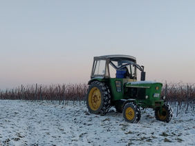 Ein Traktor steht auf einem Feld auf dem Schnee liegt.