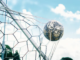 Ein Fußball in einem Tor bei blauem Himmel