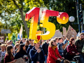 Das Foto zeigt eine Klima-Demo. Ein Jugendlicher trägt ein 1,5 Grad-Plakat.