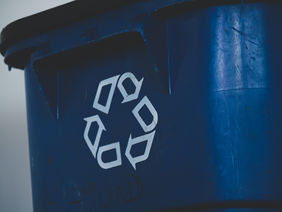 Eine Mülltonne mit einem Recycling-Symbol.