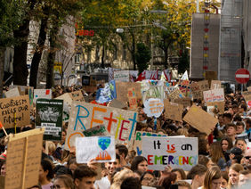 Auf einer Straße demonstrieren viele Menschen mit Schildern für das Klima. 
