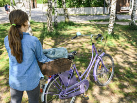 Kind legt einen Rucksack in den Fahrradkorb
