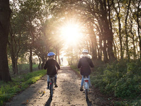 Zwei Kinder fahren Fahrrad in einem Wald.