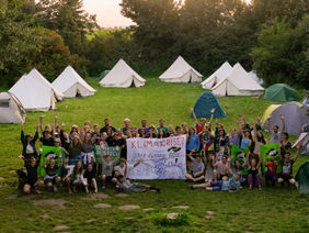 Teilnehmerinnen und Teilnehmer des Klimacamps. Im Hintergrund stehen Zelte.