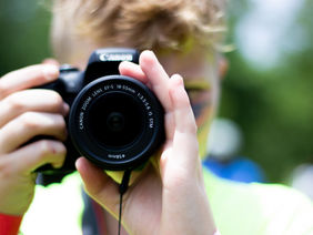 Ein Kind blickt durch den Sucher einer Kamera