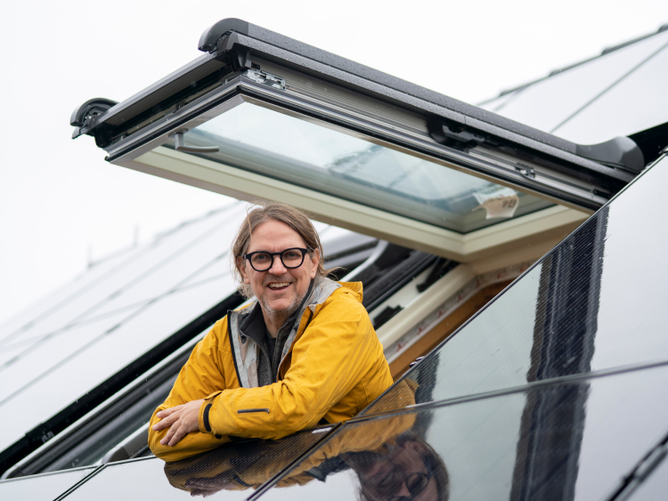 Carsten Herbert schaut aus einer Dachluke, drumherum Solarpanels.