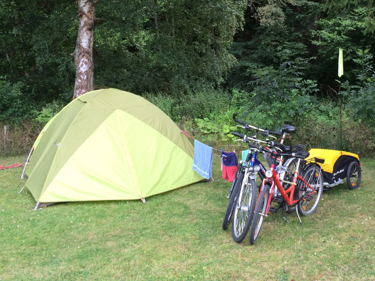 Fahrräder vor einem Zelt auf einer Wiese. 