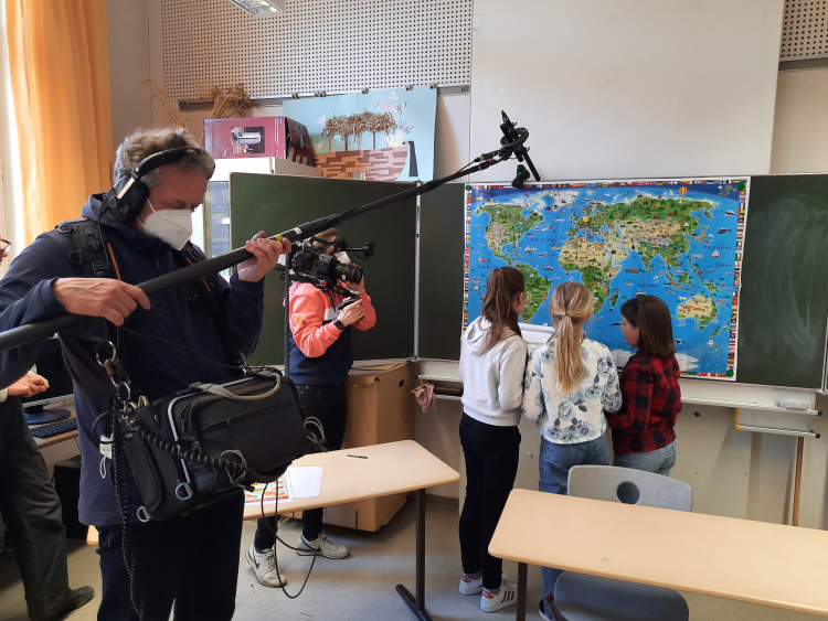 Ein Fernsehteam filmt Kinder im Klassenzimmer, wie sie etwas über Klimaschutz lernen