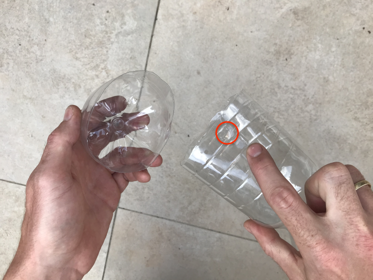 Zwei Hände halten eine aufgeschnittene Flasche (unterer Teil abgeschnitten).