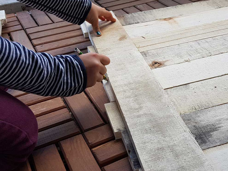 Kinderhände messen Holzbretter ab.
